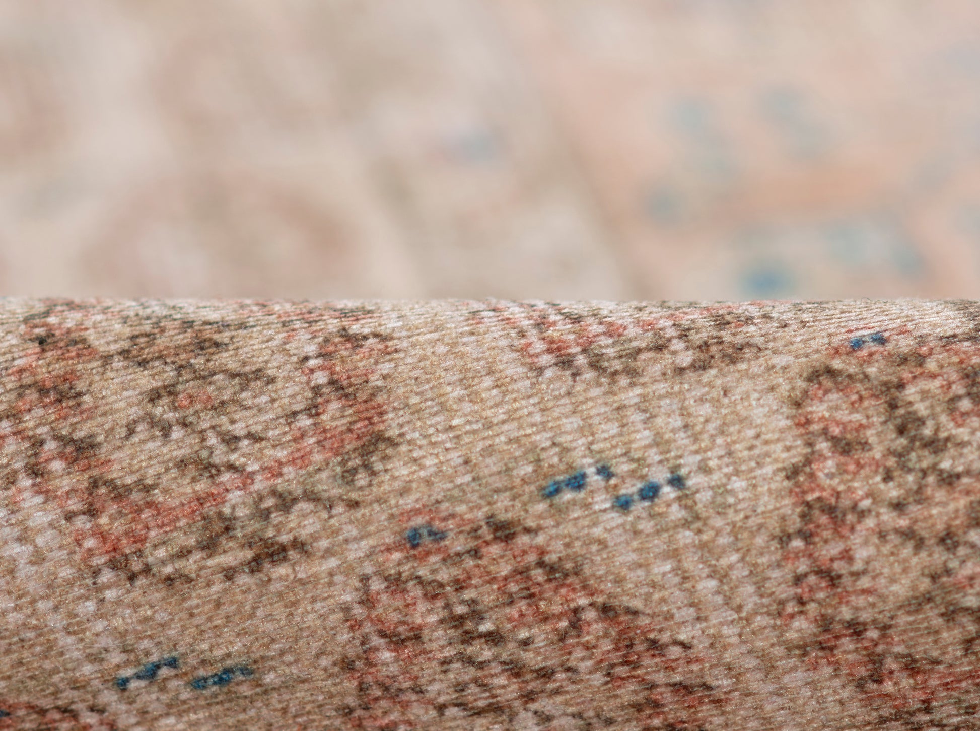 Beige Persian-style runner rug close-up with pink-red floral motifs and blue accents.