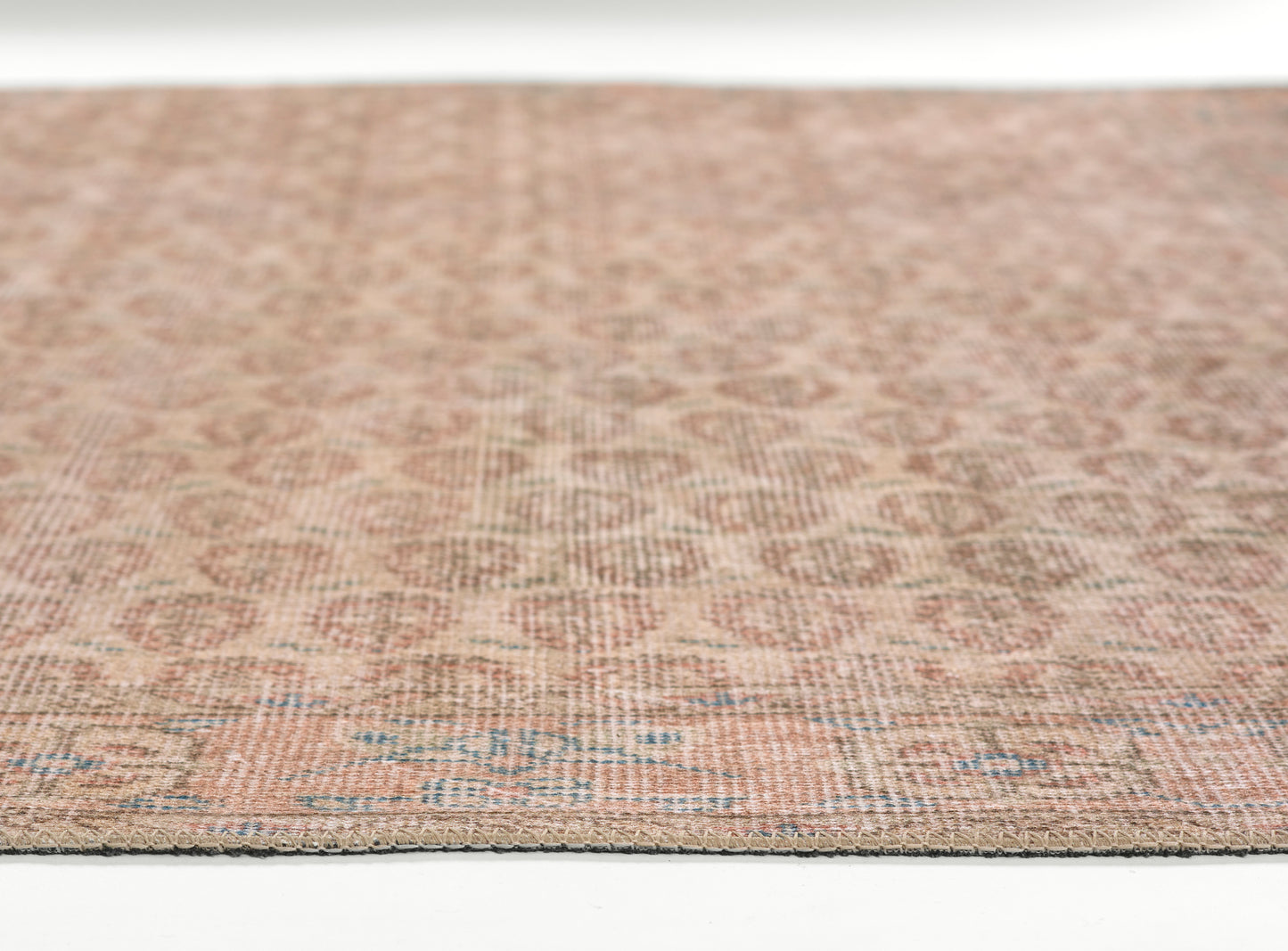Rectangular woven rug in warm beige and peach tones with blue geometric motif, flatweave look.