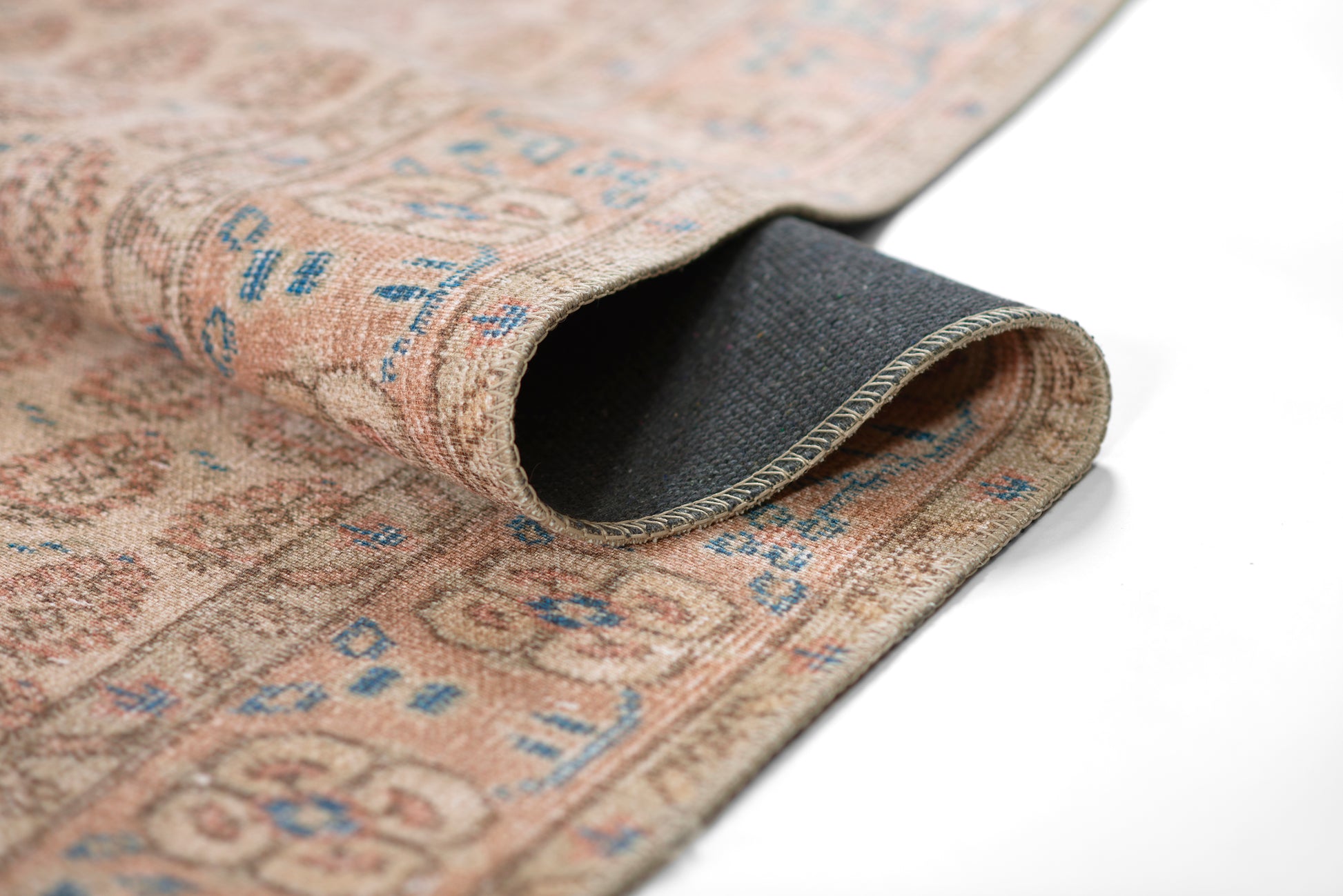 Beige oriental rug with blue motifs, rolled edge showing dark underside.