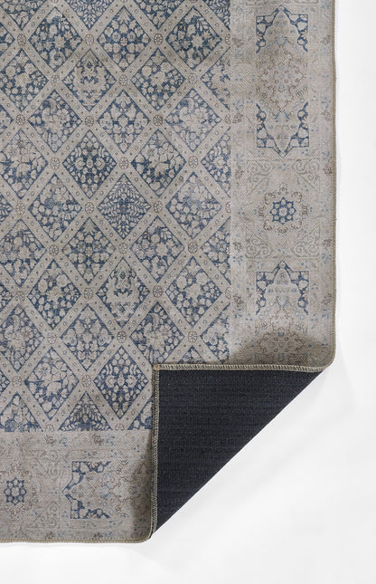 Blue & beige patterned rug with diamond lattice & floral motifs; folded corner showing dark underside.