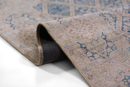 Beige woven rug with blue oriental motifs; rolled corner reveals dark underside; vintage distressed style for living room.