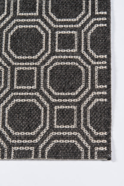 Charcoal rug with white geometric outlines forming interlocking rounded-square and octagon shapes; modern textured pattern.