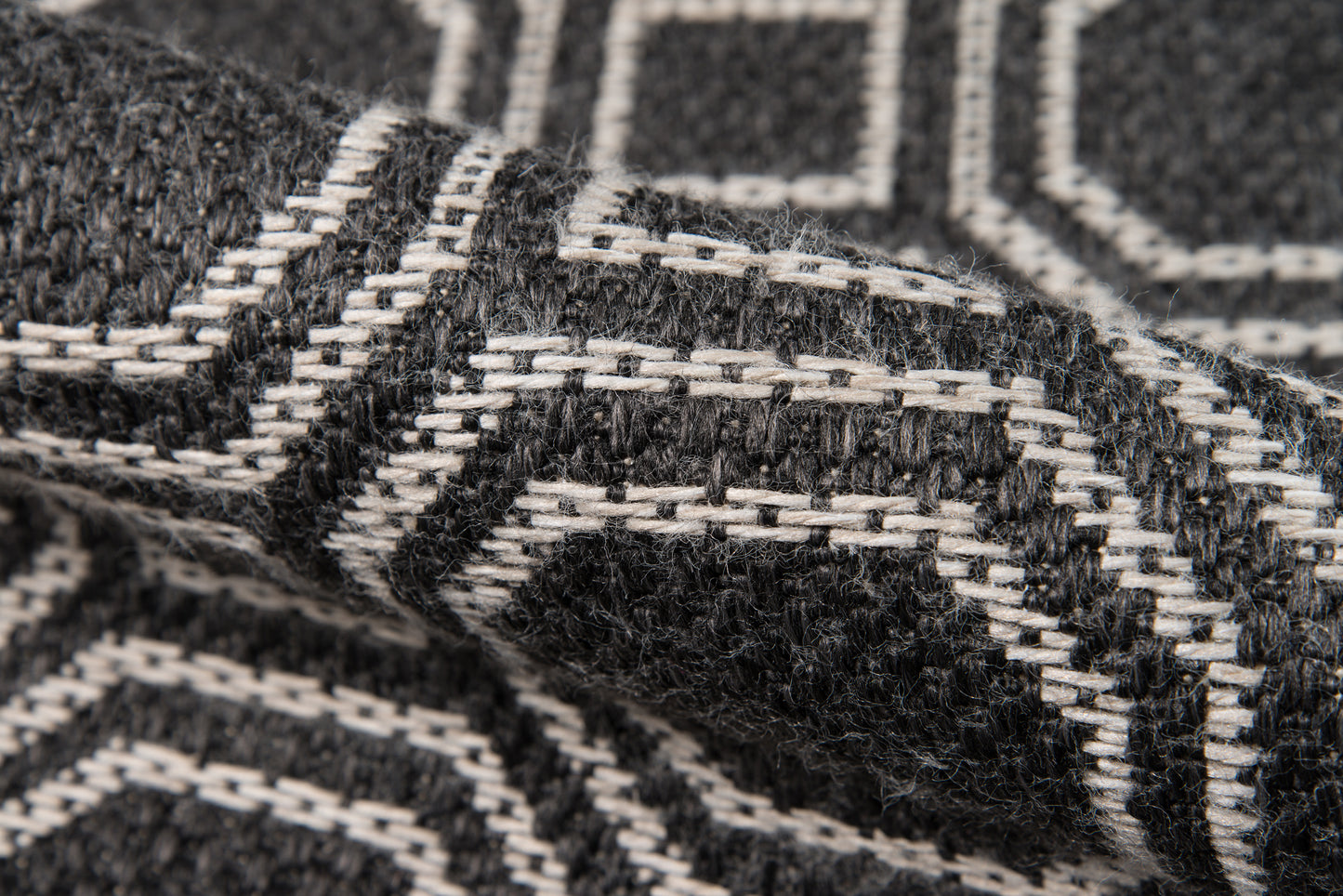 Close-up of black and white geometric woven wool rug with a thick, textured pattern.