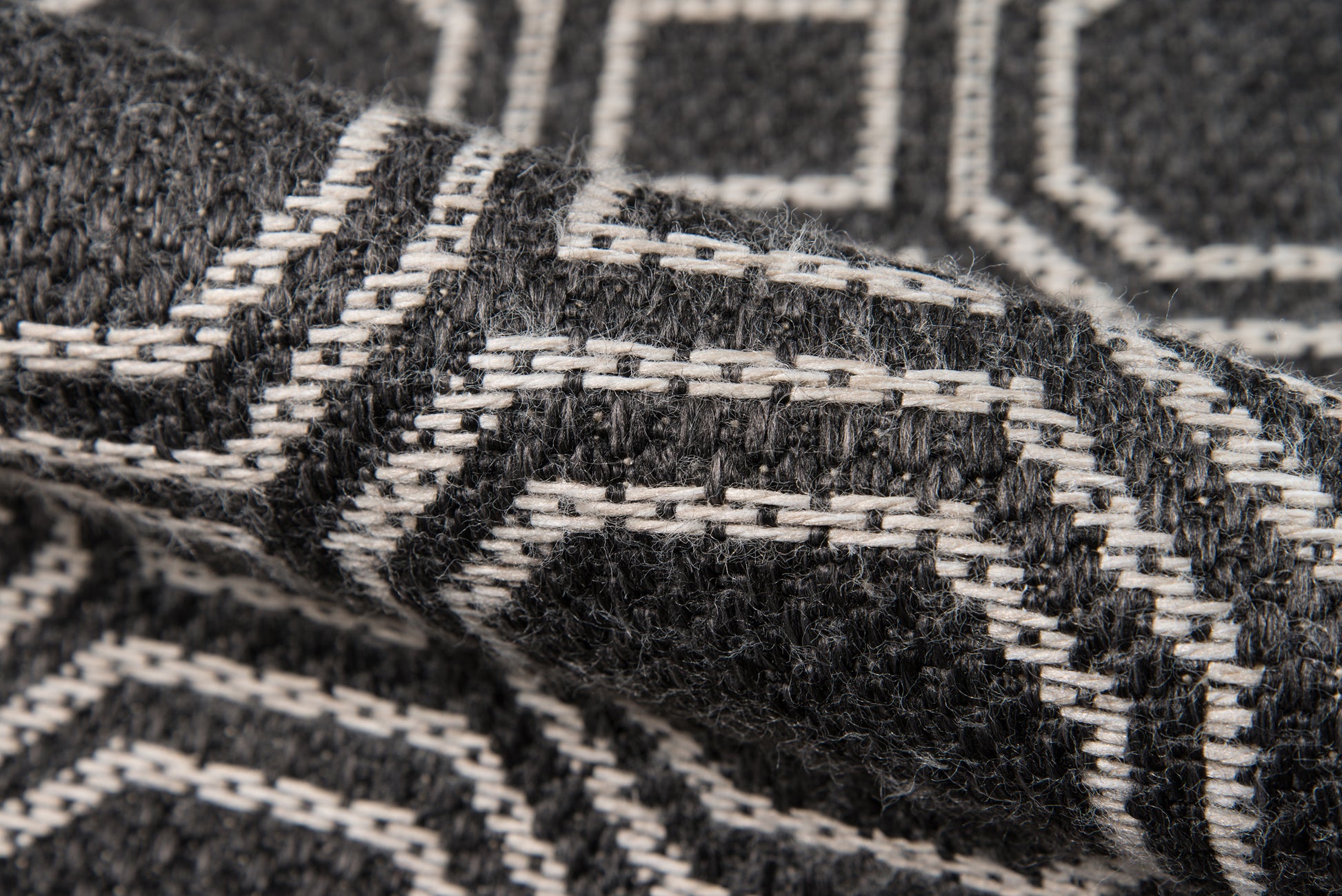 Close-up of black and white geometric woven wool rug with a thick, textured pattern.