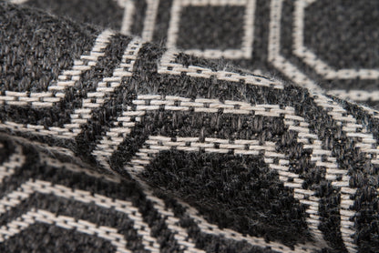 Close-up of black and white geometric woven wool rug with a thick, textured pattern.