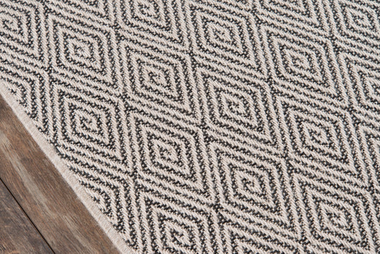 Black and white woven rug with diamond spiral pattern on wooden floor.
