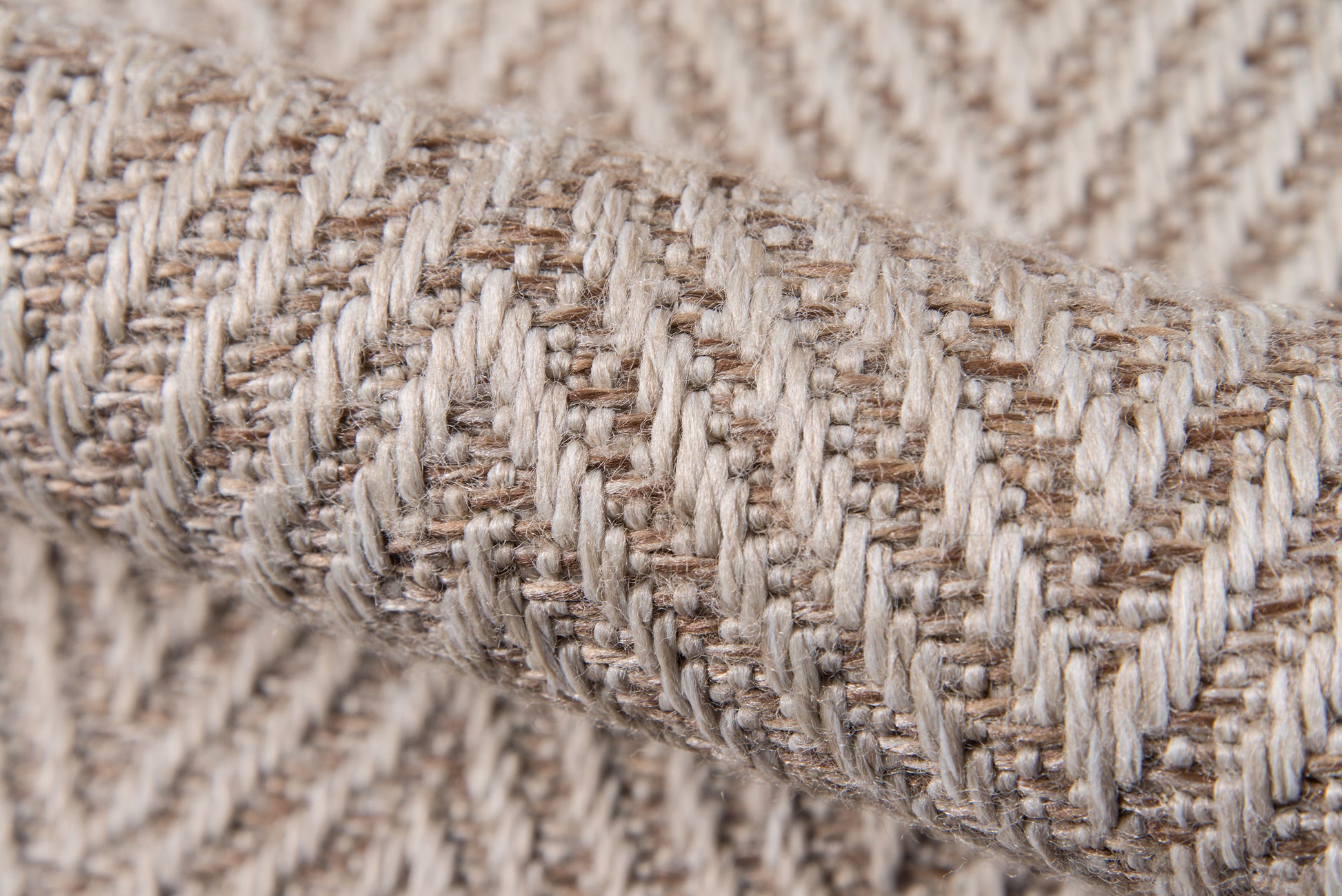 Beige woven rug close-up showing cream and tan yarns in a herringbone rib pattern.