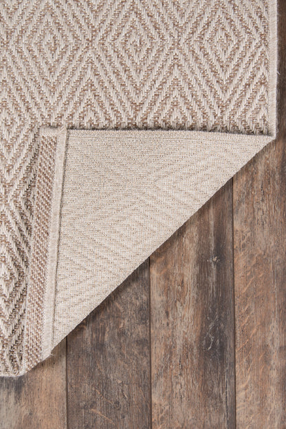 Beige geometric diamond woven rug with natural fibers; folded corner reveals underside on dark wood floor.