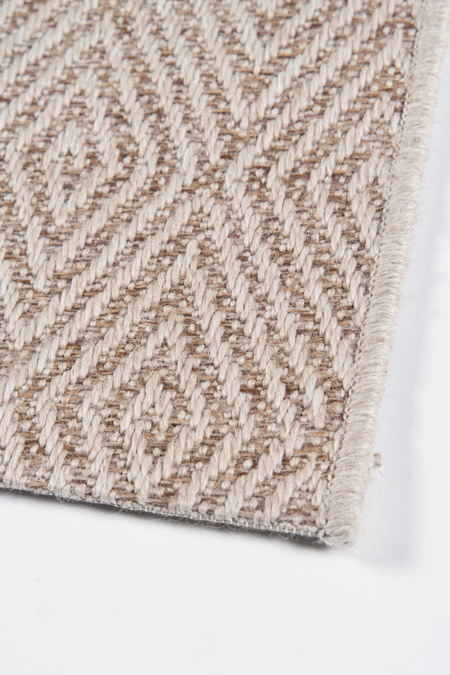 Beige geometric patterned woven rug with textured loop pile and soft fringe edge.