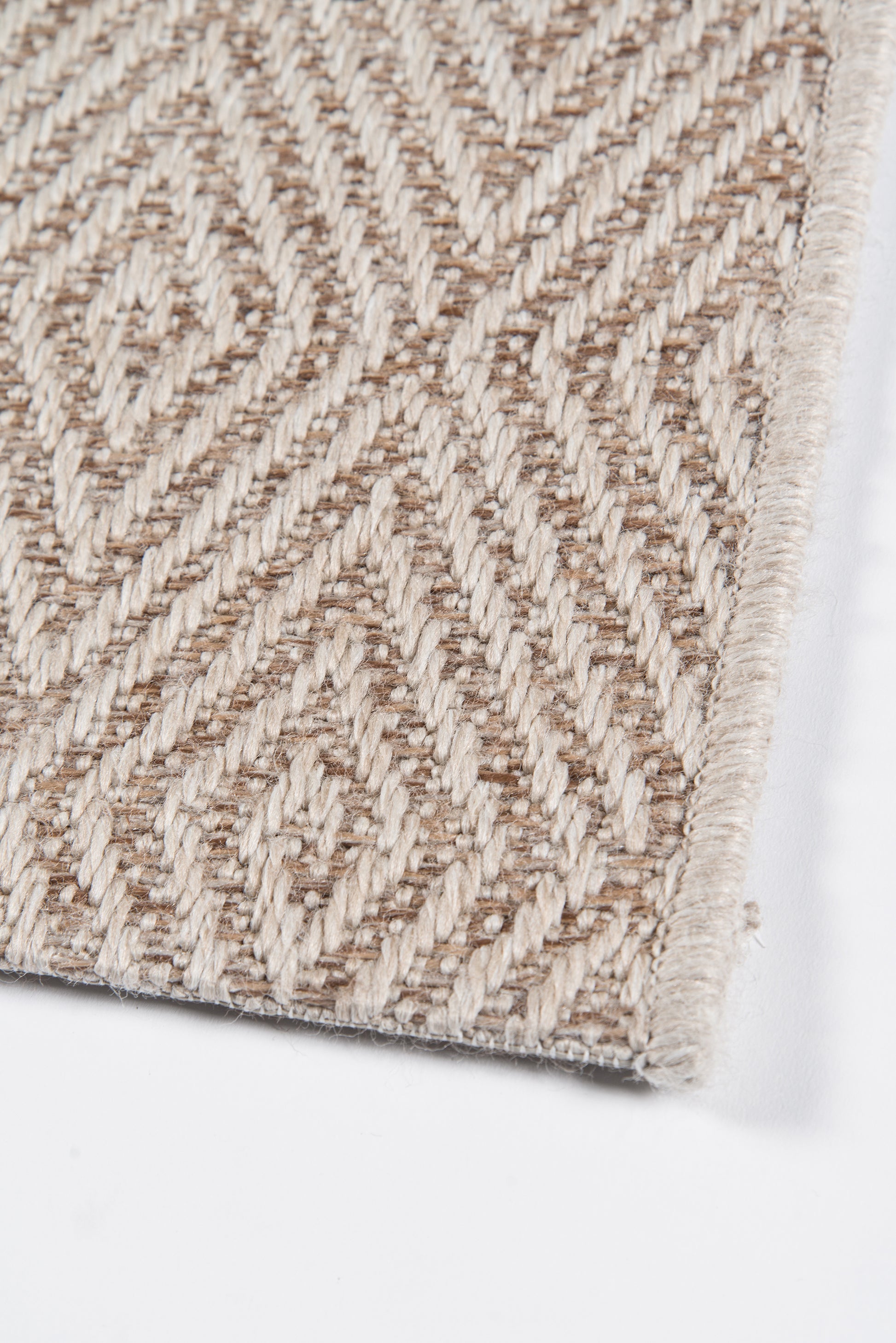 Beige geometric patterned woven rug with textured loop pile and soft fringe edge.