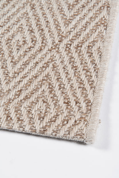 Beige geometric patterned woven rug with textured loop pile and soft fringe edge.