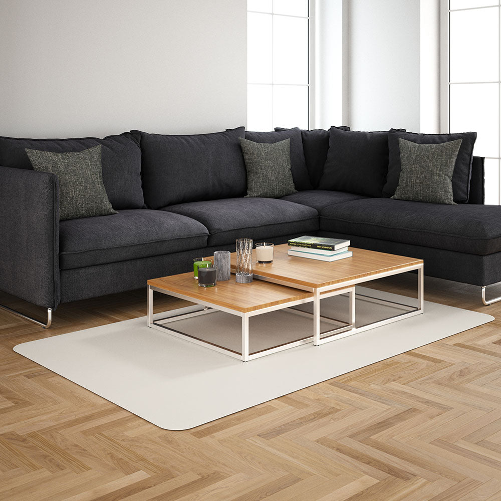 Dark gray L-shaped sectional sofa with matching cushions, two-tier light wood coffee table, white metal frame on beige rug.