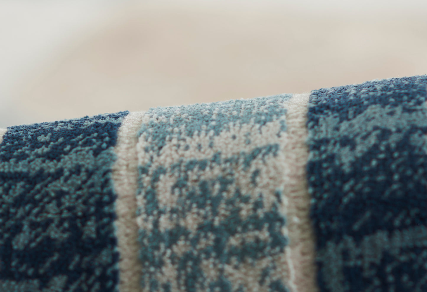 Blue woven rug close-up with ivory central stripe; plush pile, modern rustic style for living spaces.
