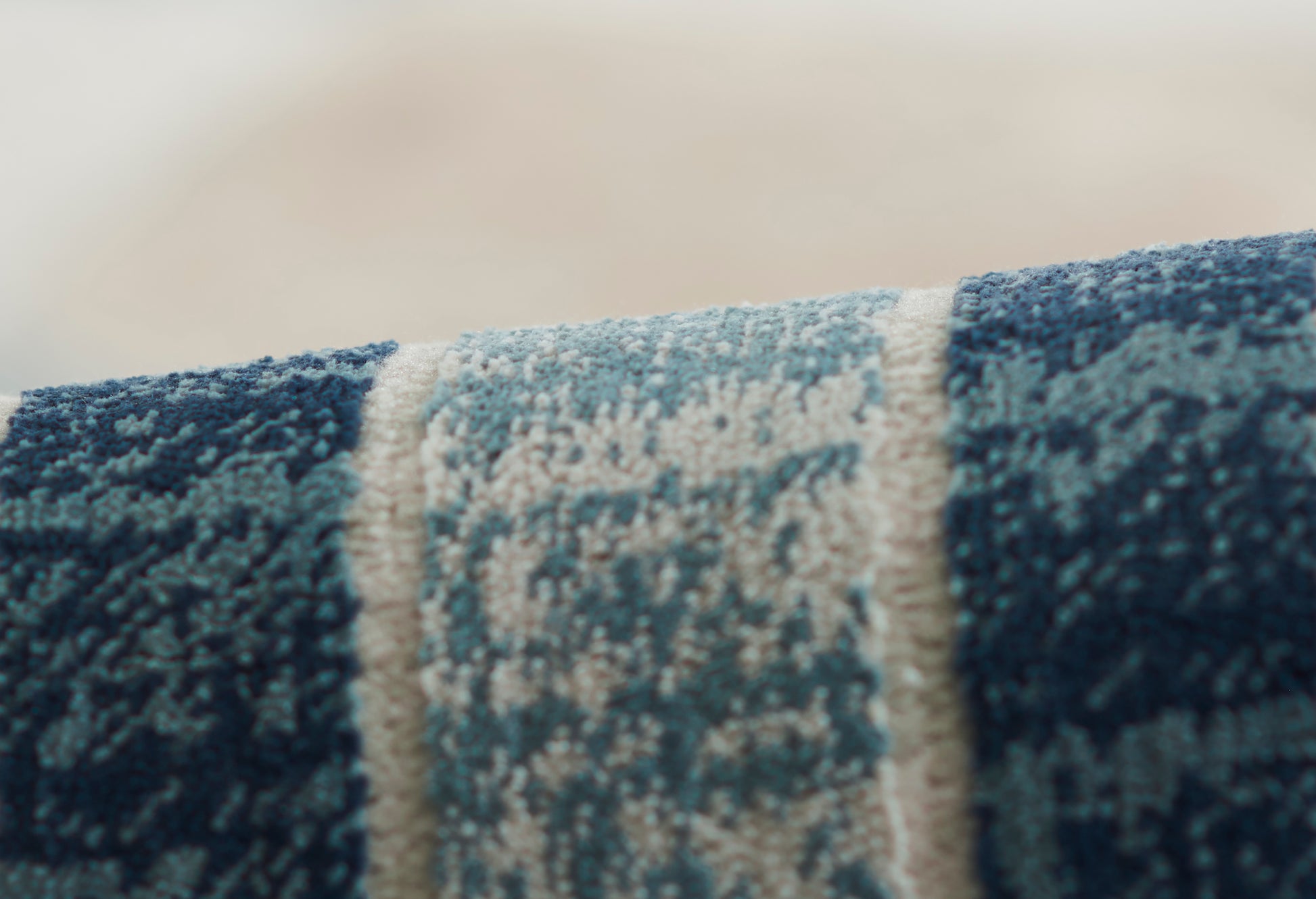 Blue woven rug close-up with ivory central stripe; plush pile, modern rustic style for living spaces.