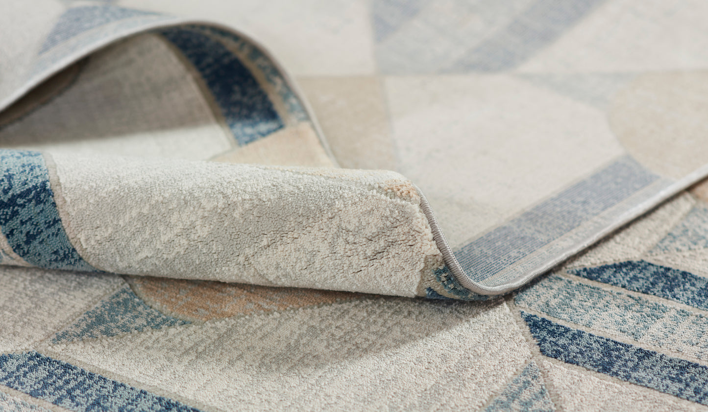 Close-up of a blue and cream woven rug with geometric diamond pattern and rolled edge.