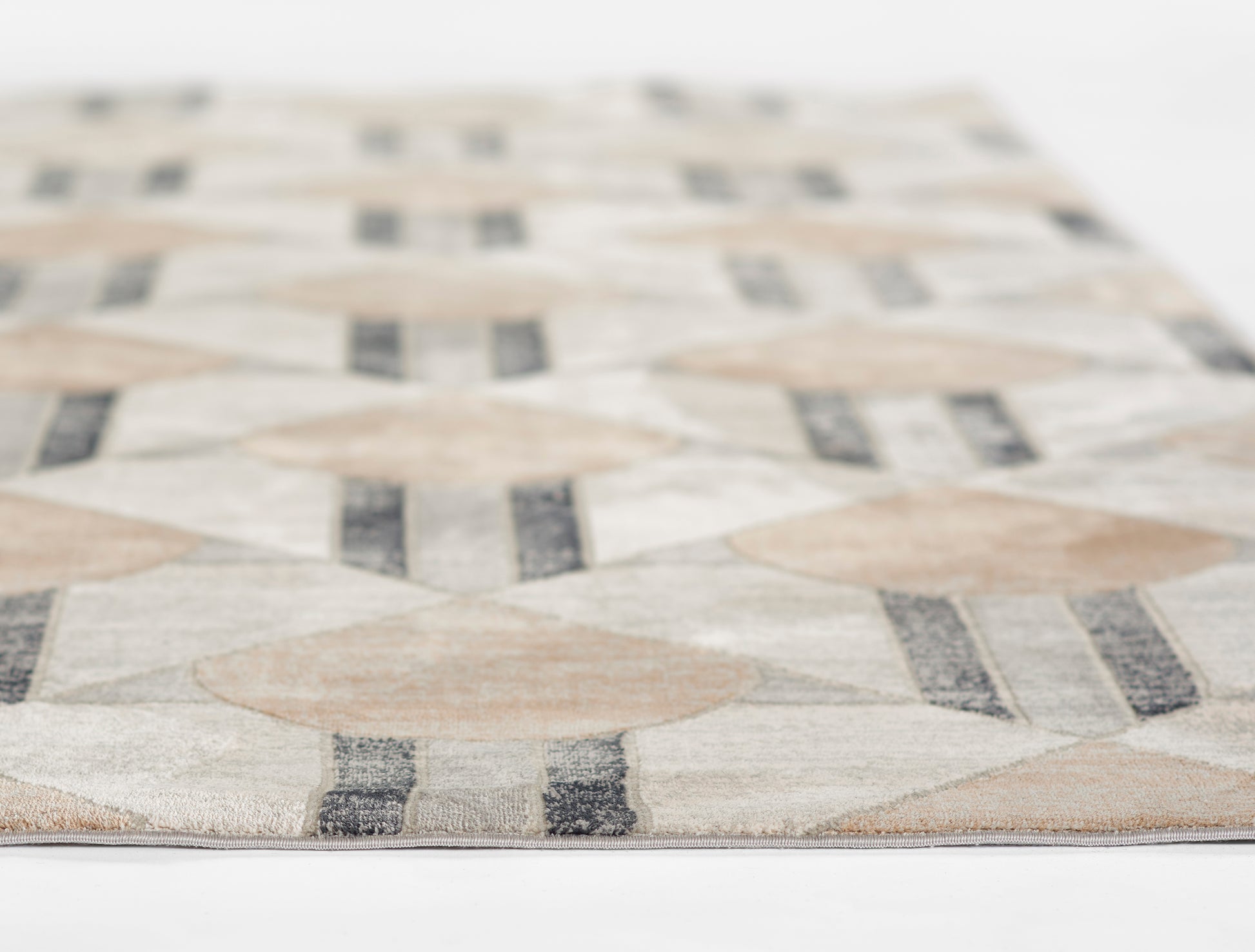 Close-up of a beige, cream and gray geometric rug with diamond motifs and striped accents, woven texture.