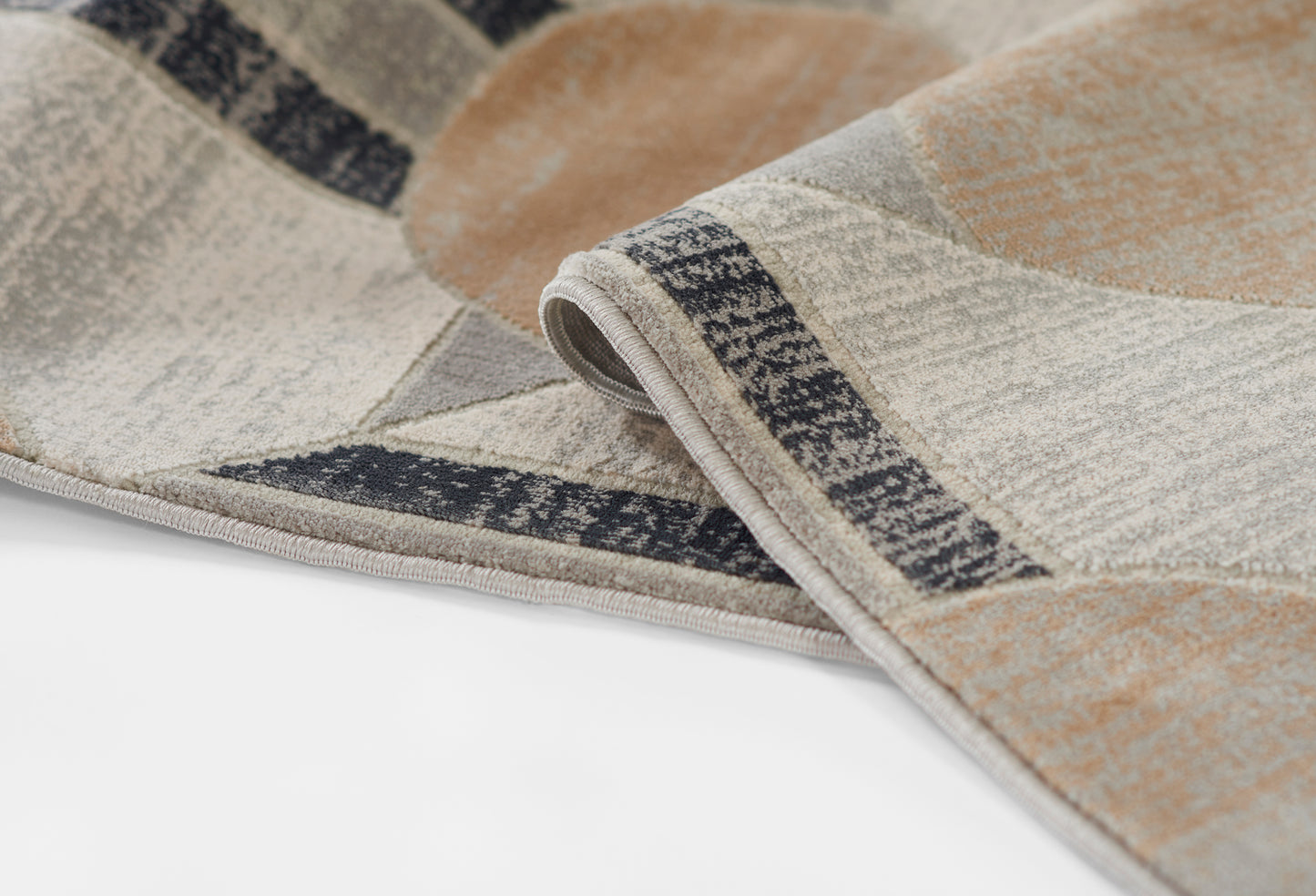 Geometric patterned woven rug in beige, taupe, ivory and gray with a dark border; folded corner detail.
