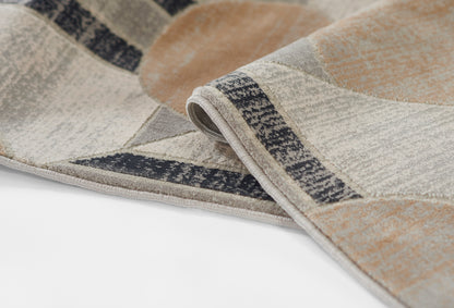 Geometric patterned woven rug in beige, taupe, ivory and gray with a dark border; folded corner detail.