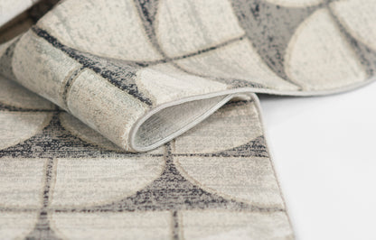 Beige and gray geometric rug with circular arc pattern; woven texture, rolled edge.