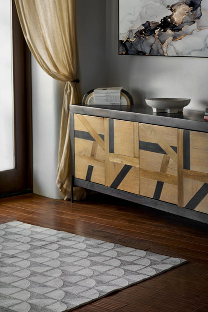 Geometric light/dark wood sideboard on a dark metal base in a living room with beige curtains.