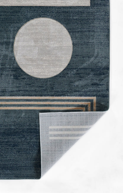 Dark blue geometric rug with a large light gray circle, beige stripes, and a folded corner revealing lighter backing.