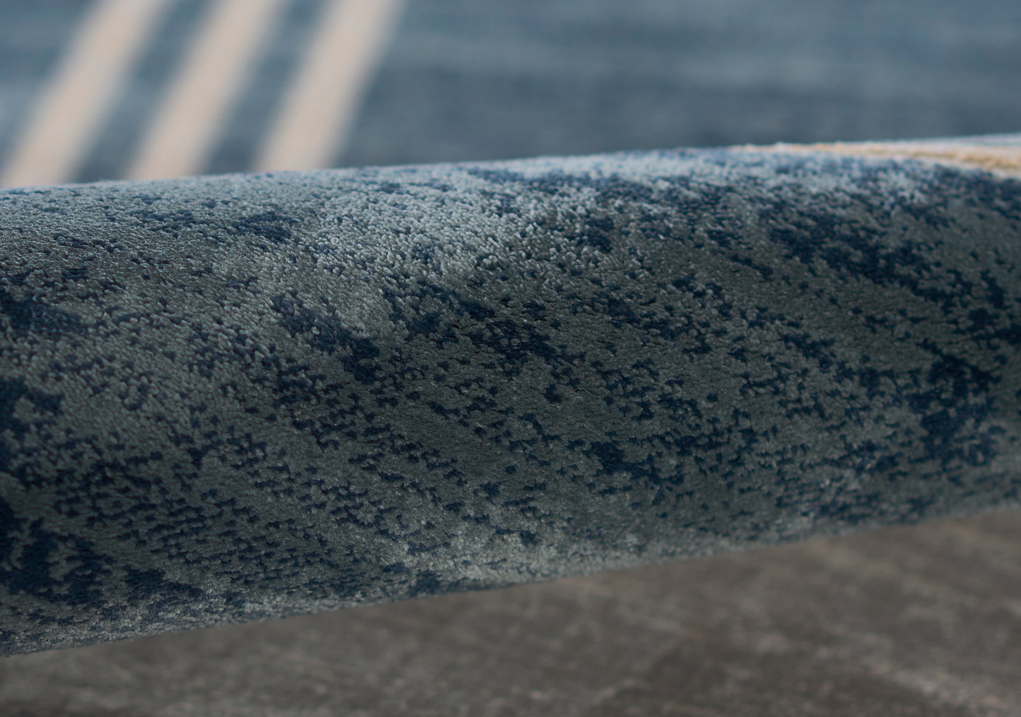 Close-up of a blue speckled cylindrical metal railing bar, powder-coated texture, curved, weathered industrial look.