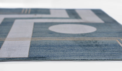 Blue and gray geometric area rug with circular motif and tan accents; modern abstract design.