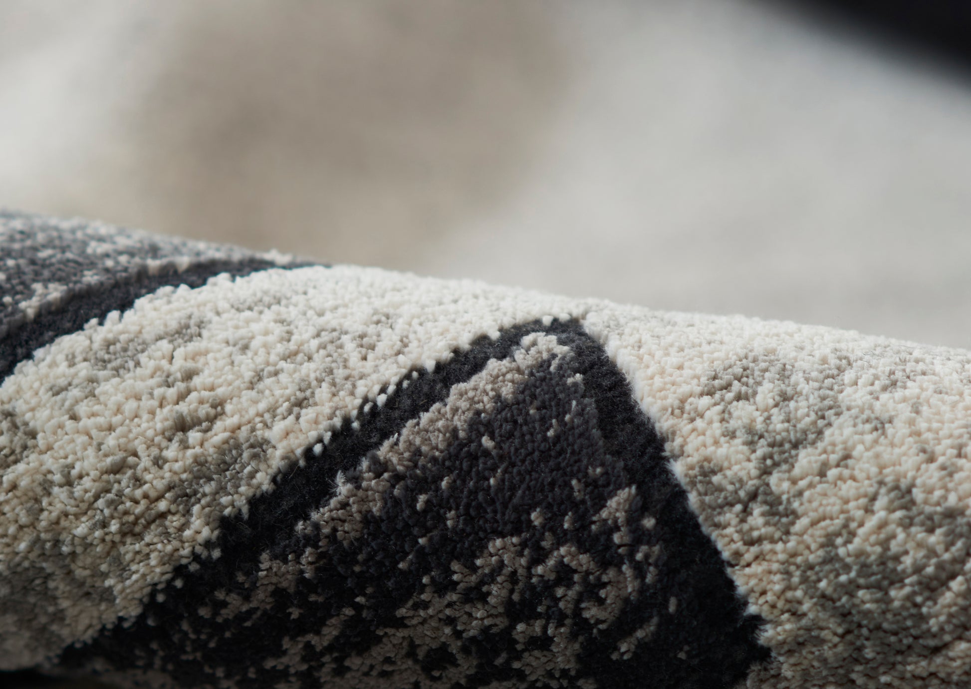 Close-up of a tufted wool rug in cream & charcoal with a geometric chevron pattern.