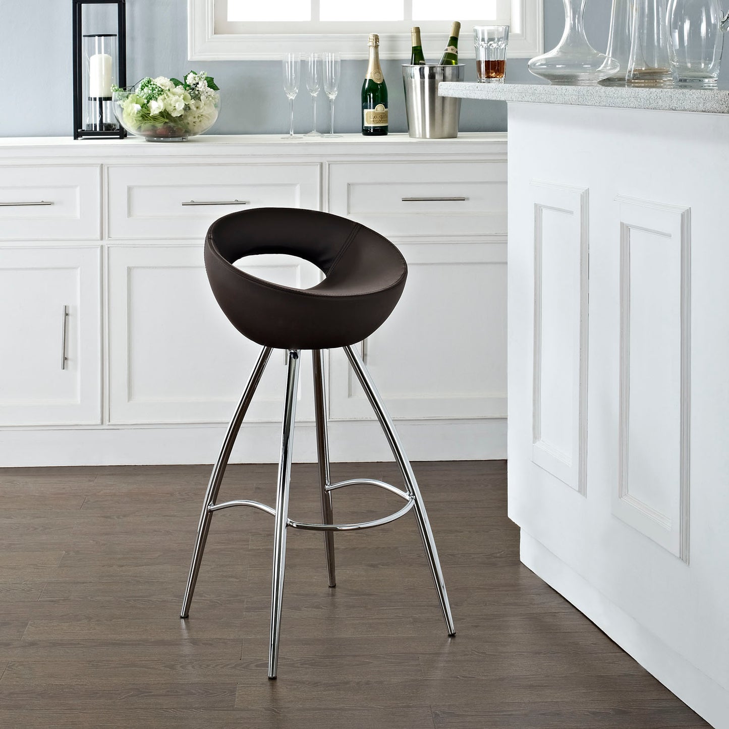 Brown donut-shaped bar stool with chrome legs and circular footrest in a bright white kitchen.