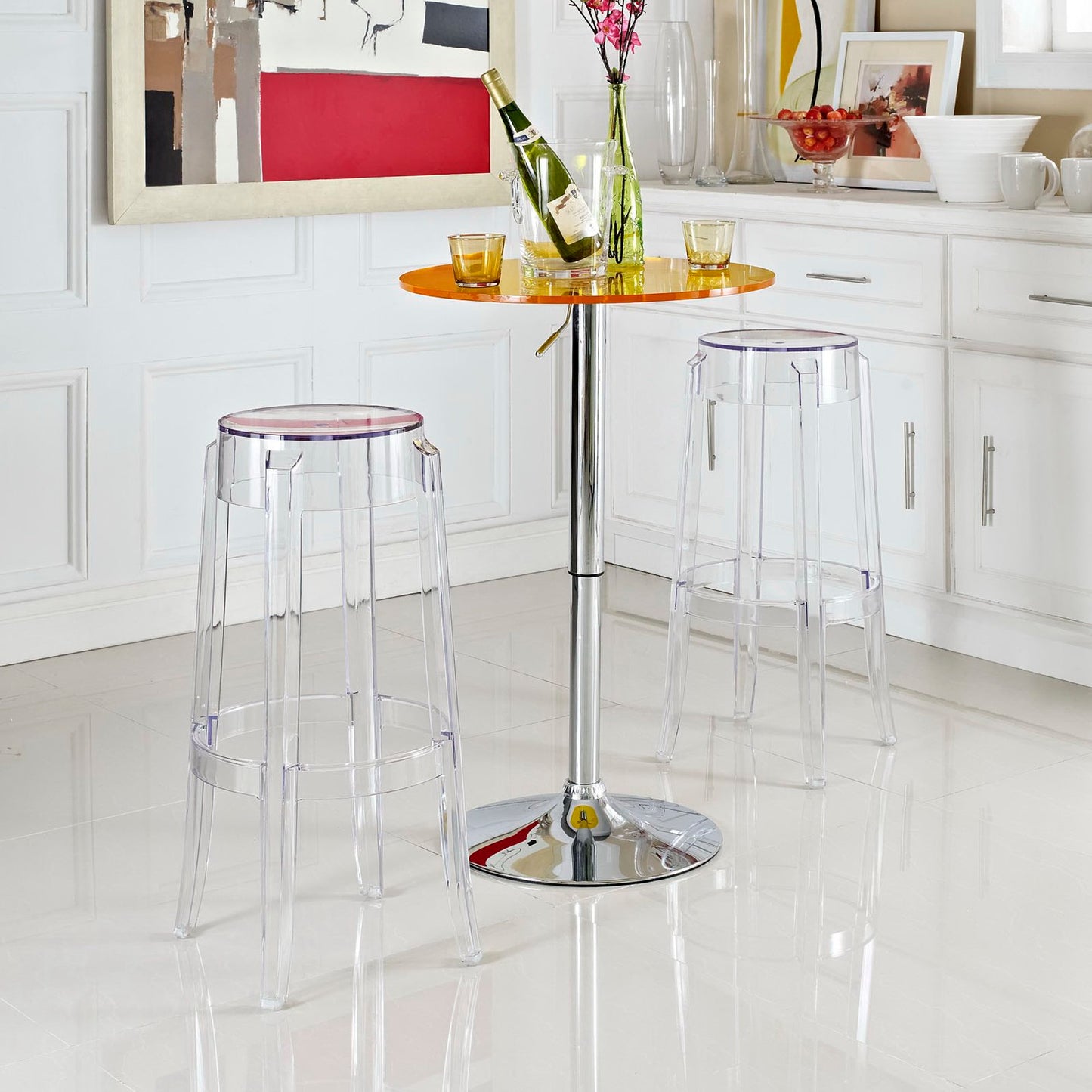 Clear acrylic bar table with orange round top and chrome pedestal, paired with transparent stools in a modern kitchen.