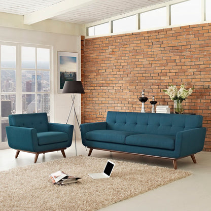 Teal blue mid-century fabric sofa and matching armchair in a bright loft with exposed brick and beige shag rug.