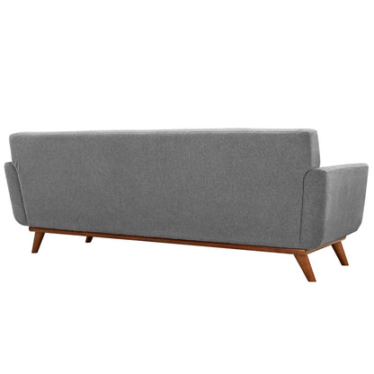 Back view of gray fabric sofa with wooden tapered legs and rounded arms, mid-century style.