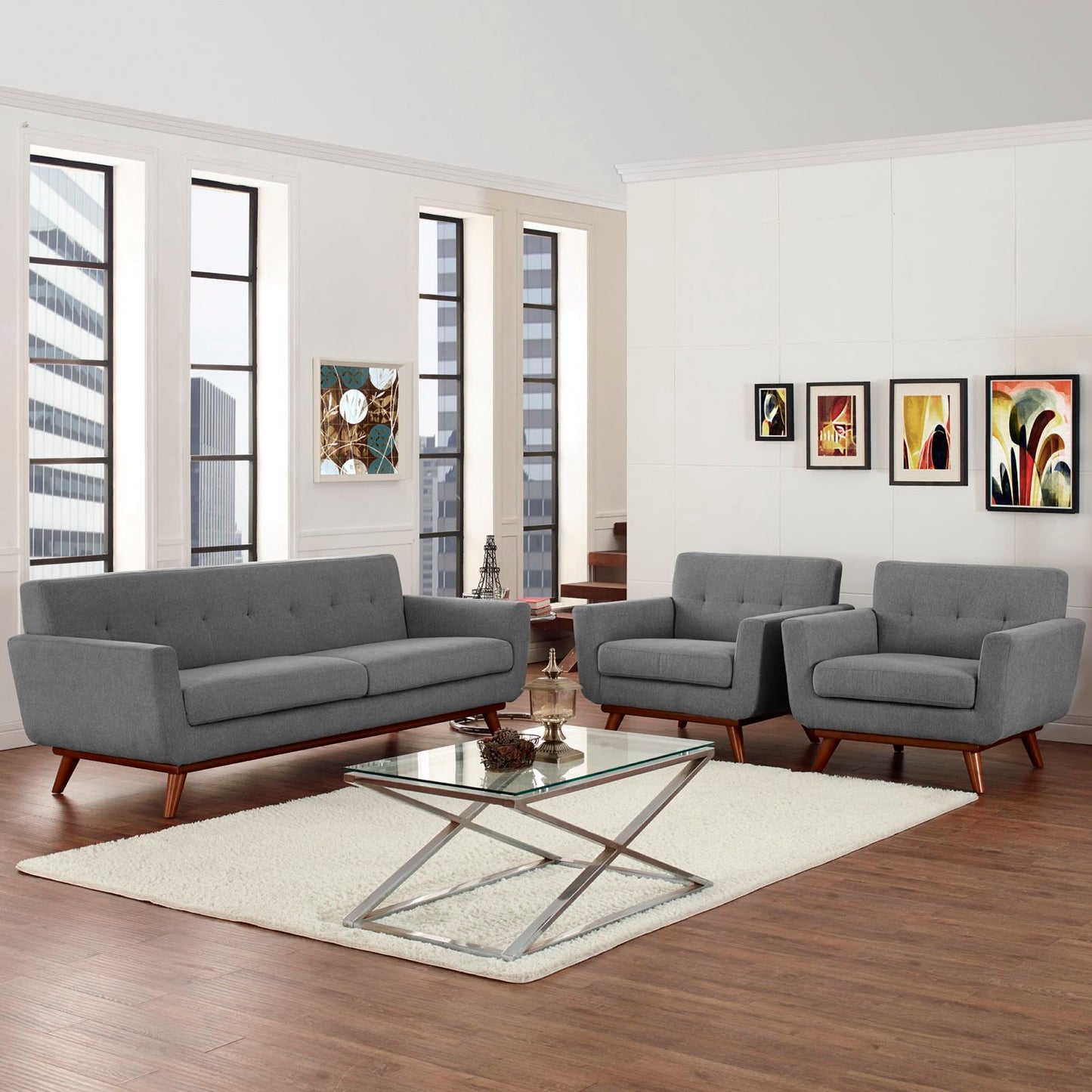 Gray mid-century sofa and two armchairs with wooden legs, glass coffee table on a cream rug in a modern living room.