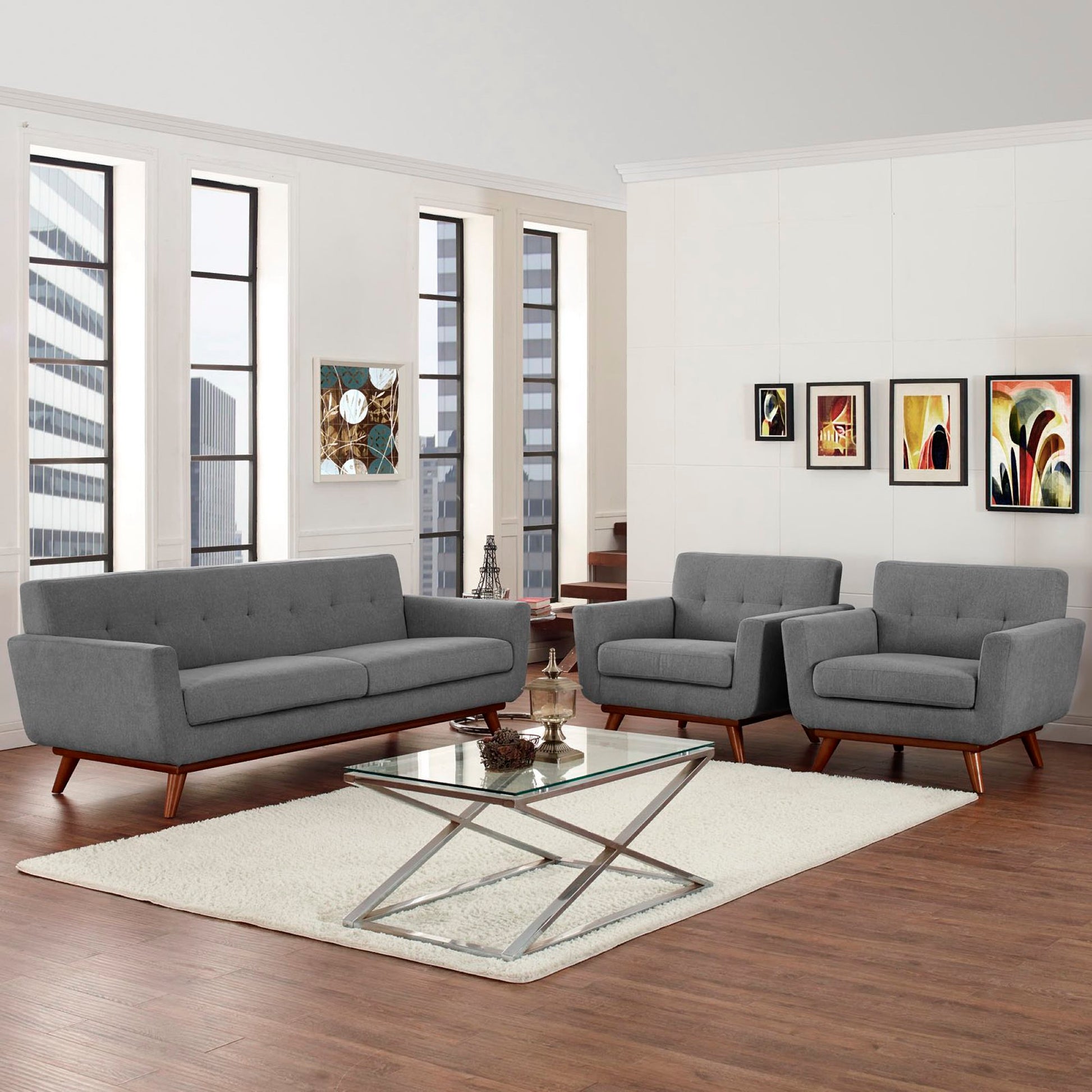 Gray mid-century sofa and two armchairs with wooden legs, glass coffee table on a cream rug in a modern living room.