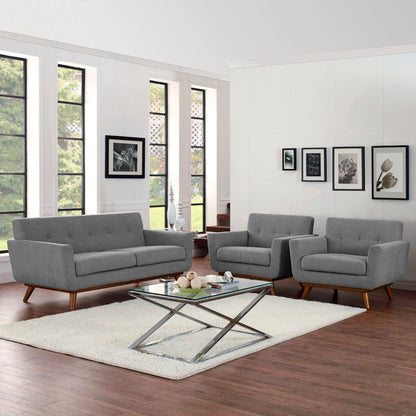 Grey fabric mid-century modern sofa and chairs with a glass-top metal coffee table on a cream rug in a bright living room.