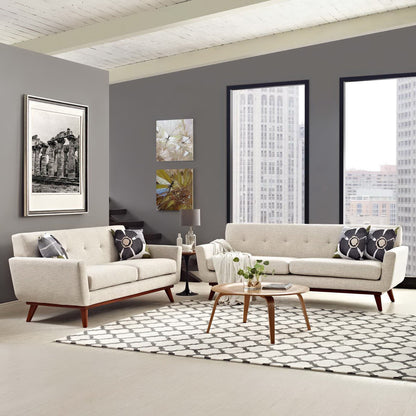 Neutral beige mid-century sofa set with wood legs, round wood coffee table, patterned rug, city view windows.