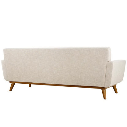 Rear view of beige linen sofa with mid-century wooden legs, rounded arms, soft neutral fabric.