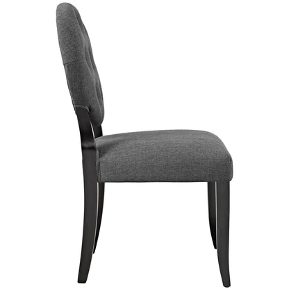 Gray upholstered dining chair with dark wood legs, curved back and cushioned seat, side view.