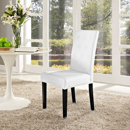 White tufted dining chair with black legs in a bright sunlit room beside a round white table with flowers and apples.
