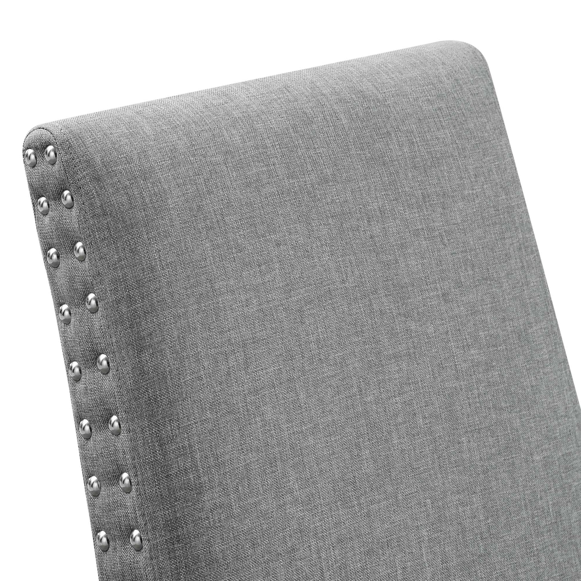 Gray fabric upholstered chair back with silver nailhead trim along the edge.