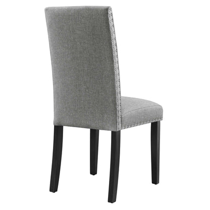 Grey fabric dining chair with studded nailhead trim along the edges, high back, and dark wood legs.