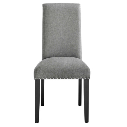 Grey fabric dining chair with tall back, curved padded seat, nailhead trim along rim, dark wooden legs.