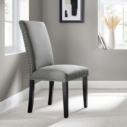 Grey upholstered dining chair with tall back, nailhead trim, and dark curved wood legs.