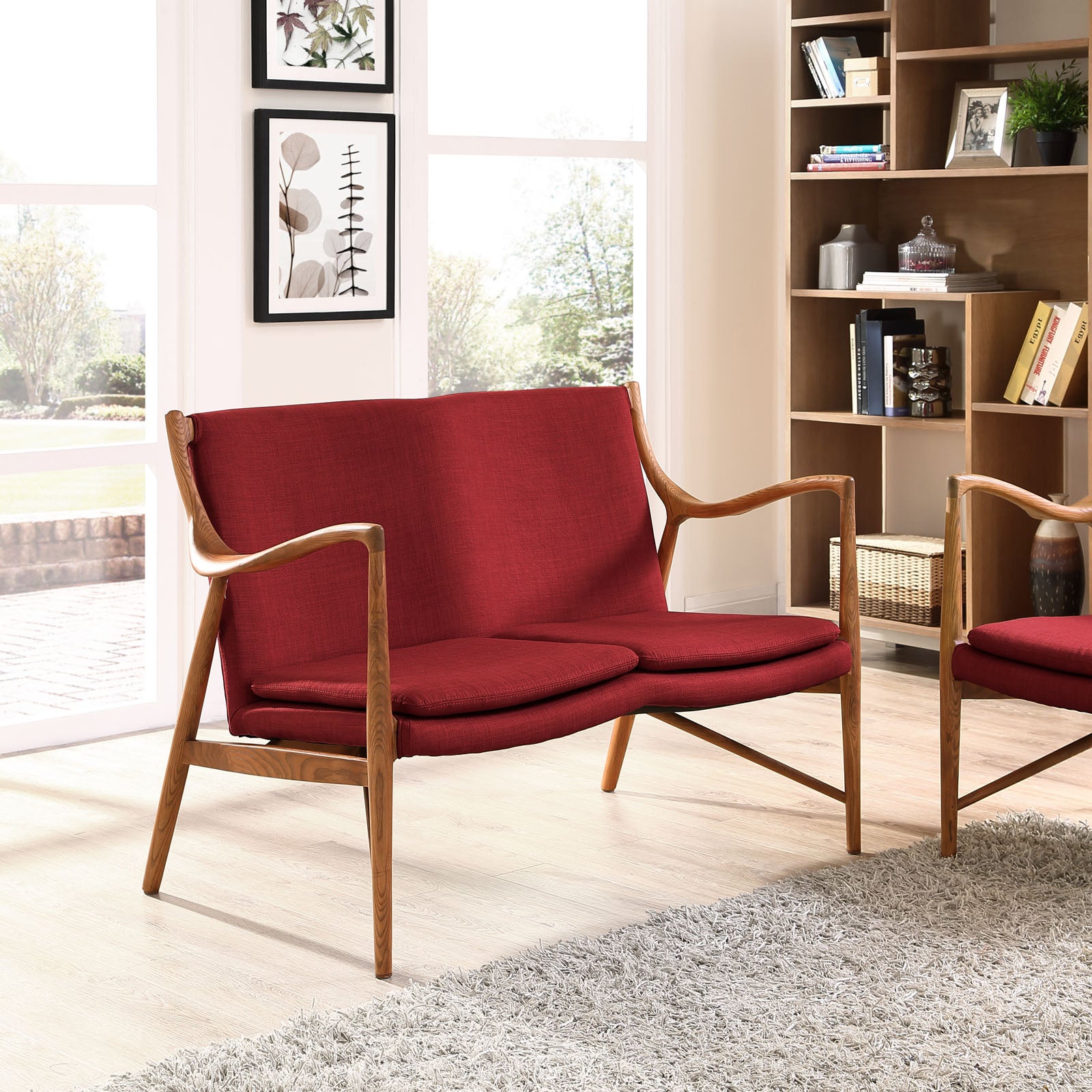 Red fabric loveseat with curved wooden arms and light wood legs in a bright, mid-century modern living room.
