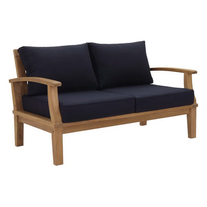 Natural wood patio loveseat with navy cushions and curved armrests.