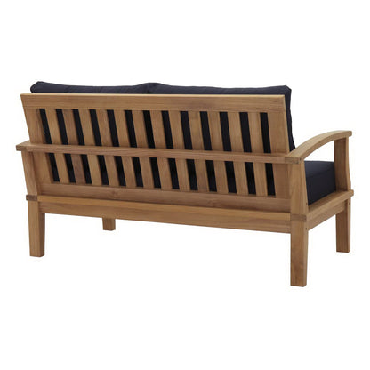 Natural wood outdoor sofa with navy cushions, slatted back, curved armrests, garden seating.