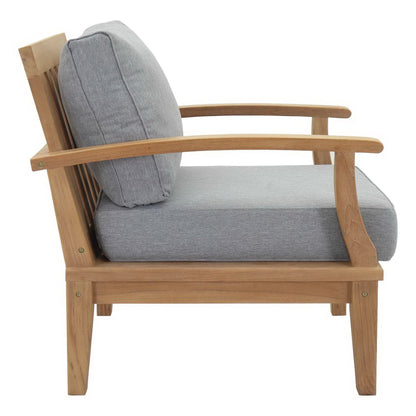 Natural wood outdoor chair with light gray cushions and curved armrests.