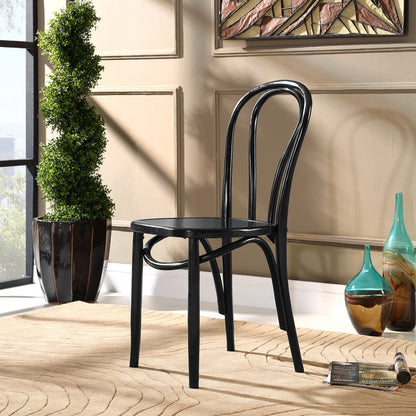 Black bentwood cafe chair with curved back in a beige-walled room on a woven rug beside a green topiary & glass vases.