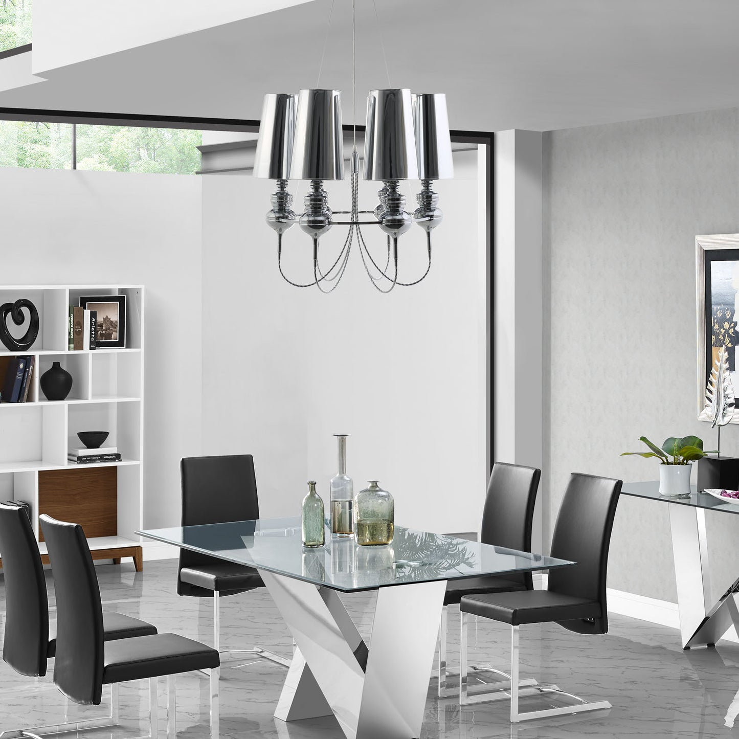 Stainless steel chandelier with a modern sculptural design hanging above a dining table in a bright dining room.