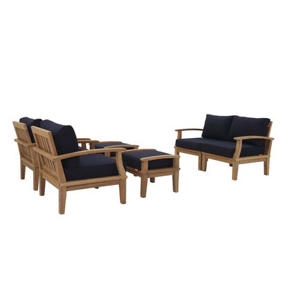 Teak outdoor six-piece seating set with navy cushions: two armchairs, a loveseat, and a matching ottoman.